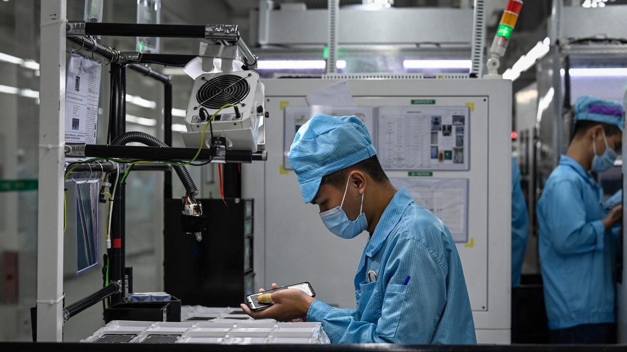 Employees working on a smartphone assembly line 